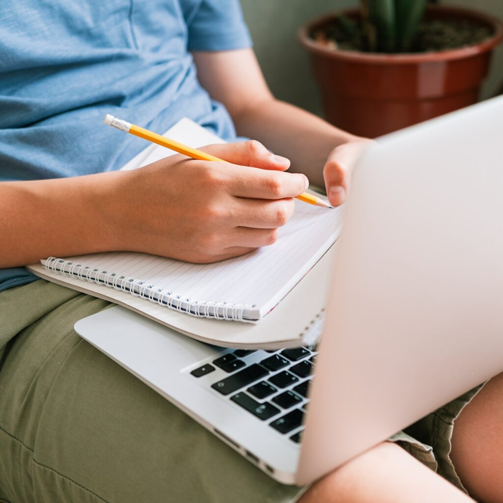 Teen boy lies on the floor in front of a laptop. Classes at home. Remote training.